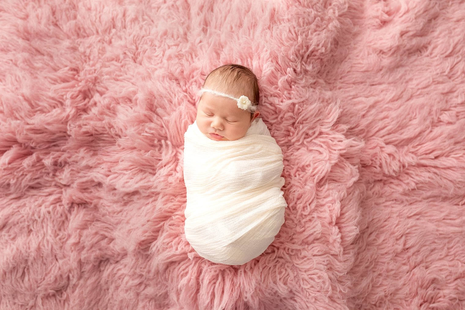 Newborn baby girl on pink flokati fur
