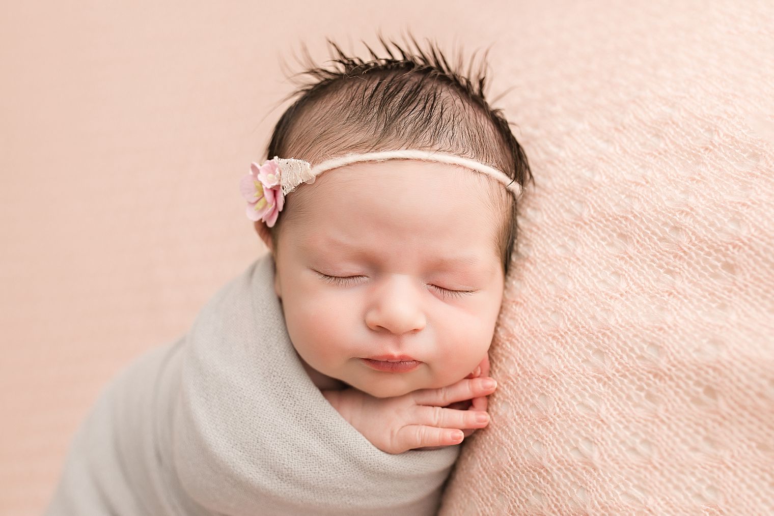 Newborn baby in pink and gray blankets