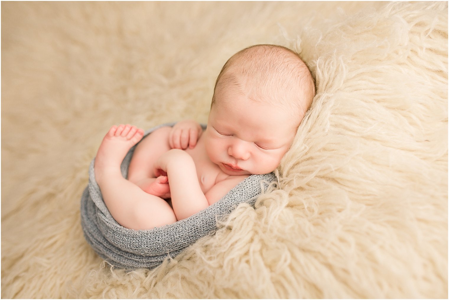 Newborn boy on cream flokati fur