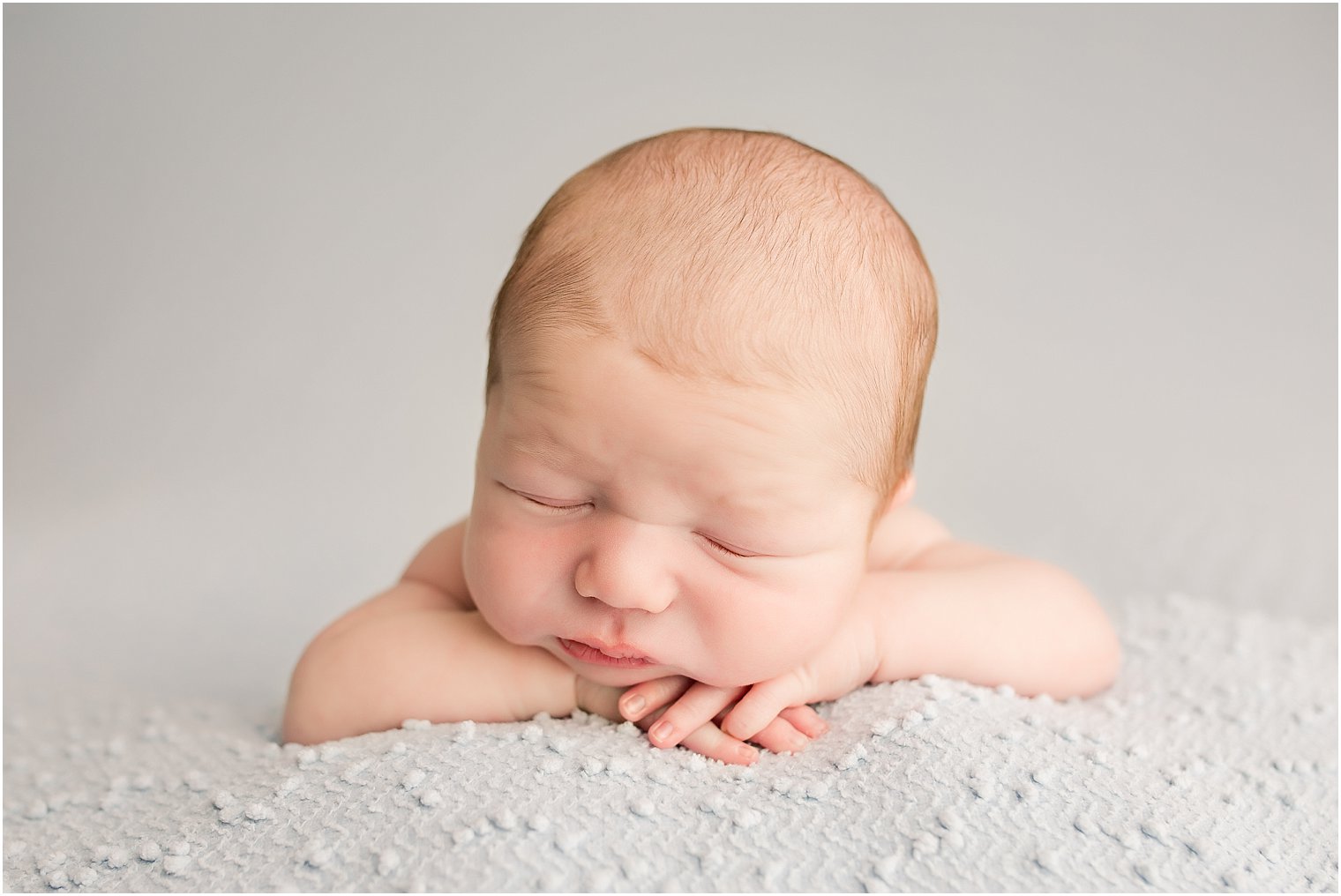 Newborn baby in chin on hands pose