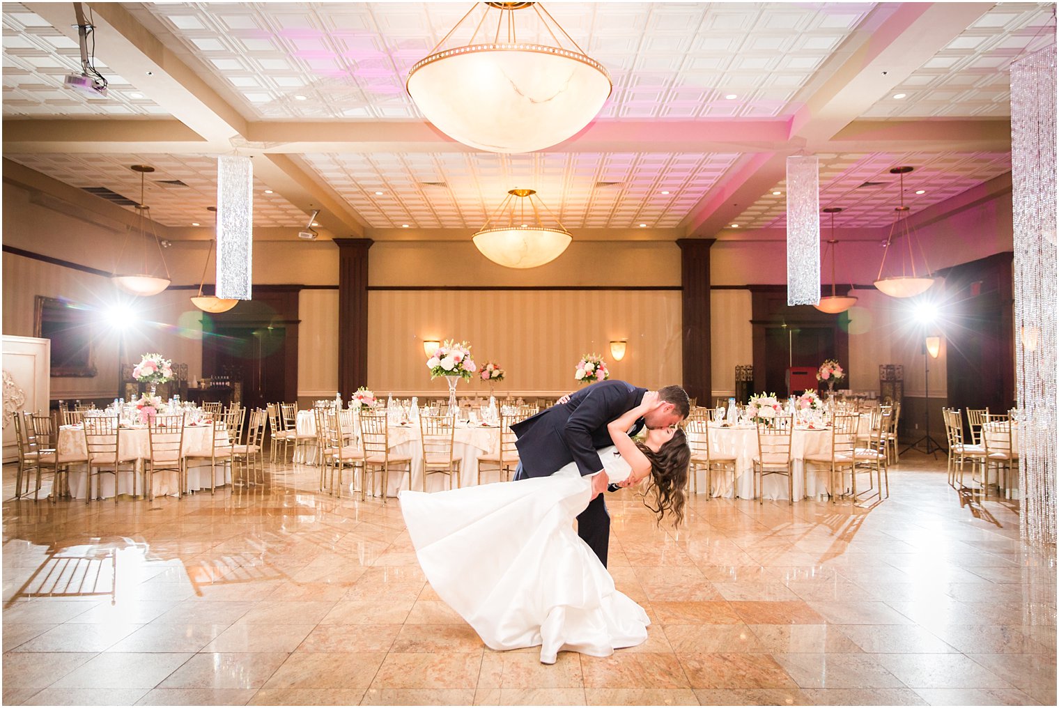 Groom dipping bride in empty ballroom