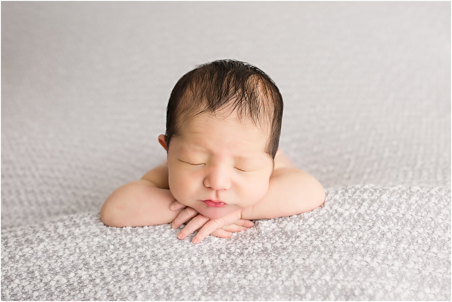 Newborn boy on gray blanket