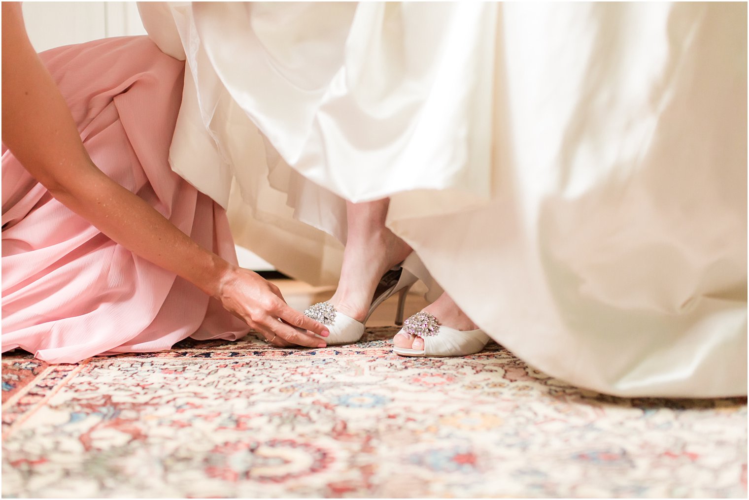 Bridesmaid putting on bride's shoes