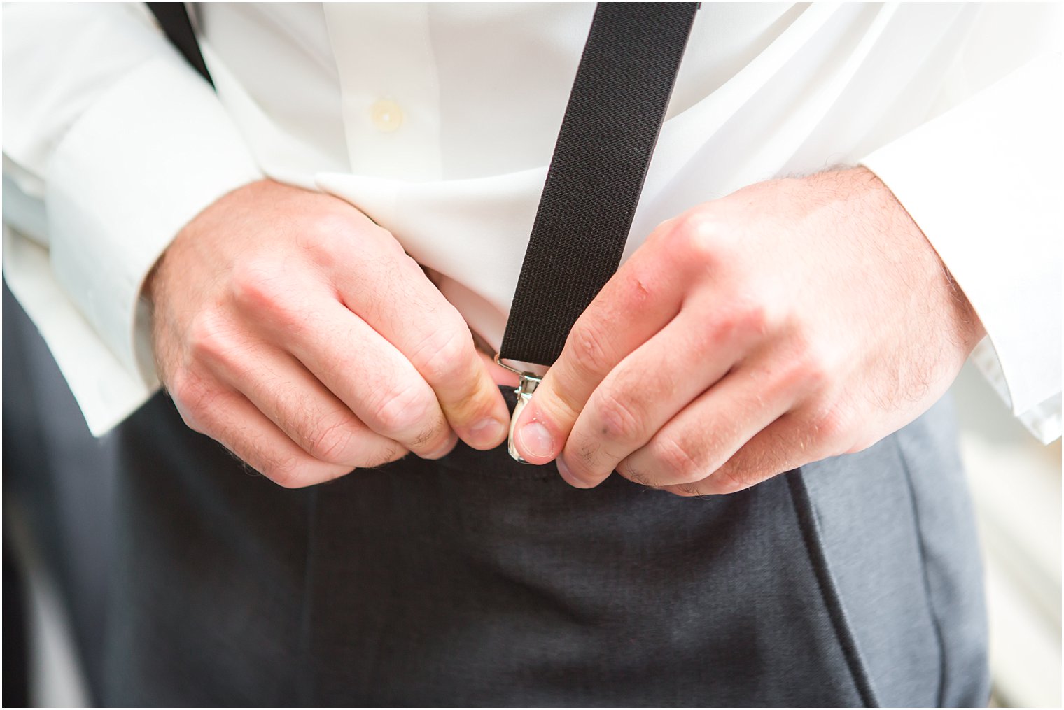 Groom putting on suspenders