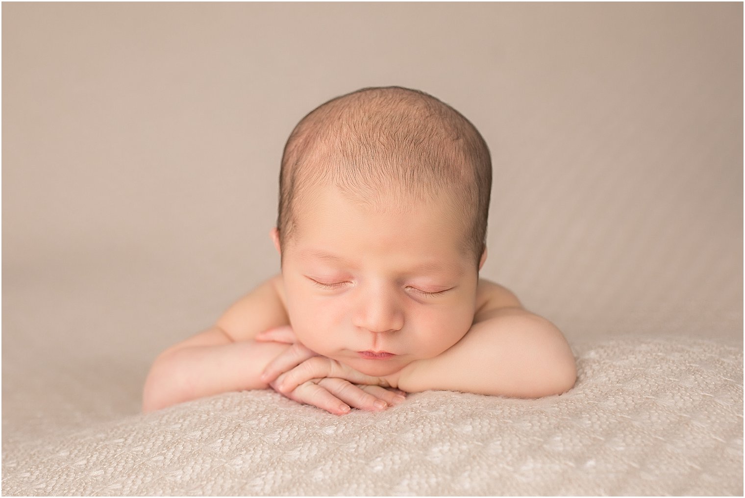 Newborn in chin on hands pose