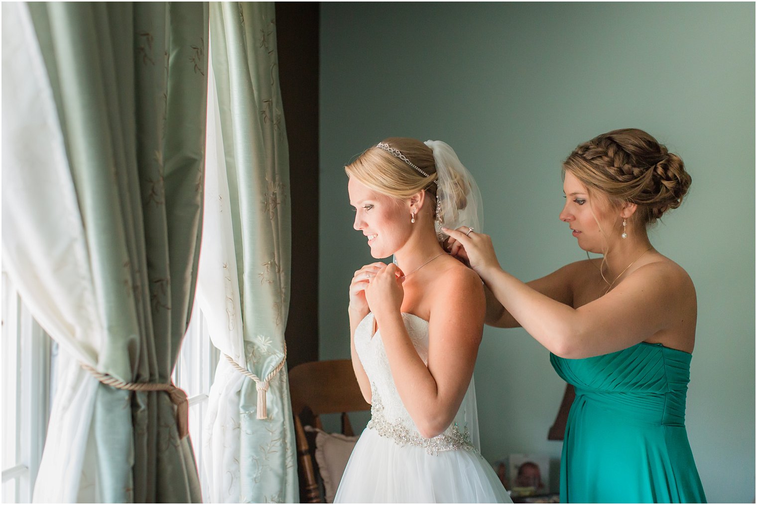 Maid of honor helping bride get dressed