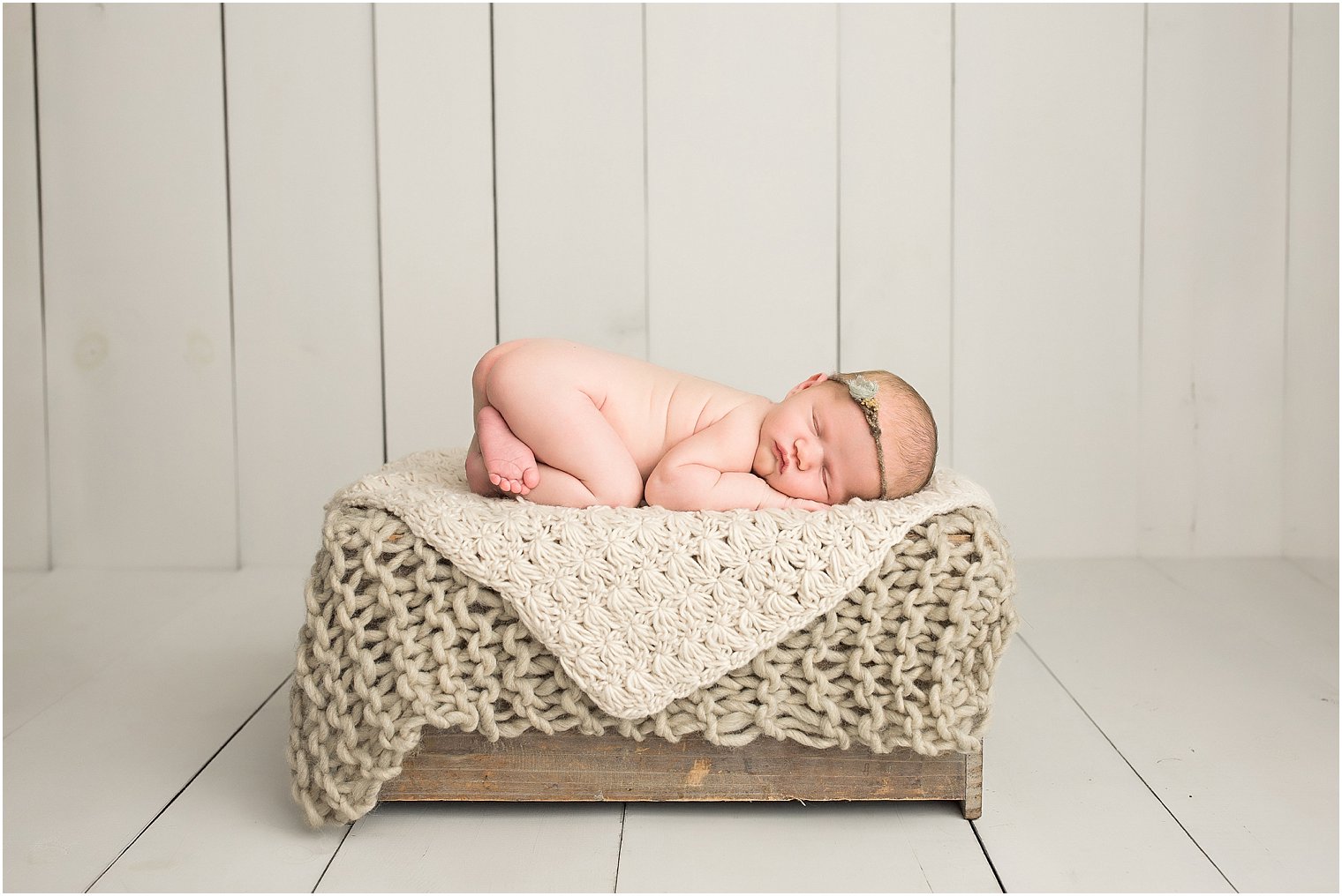 Newborn girl in neutrals on a crate