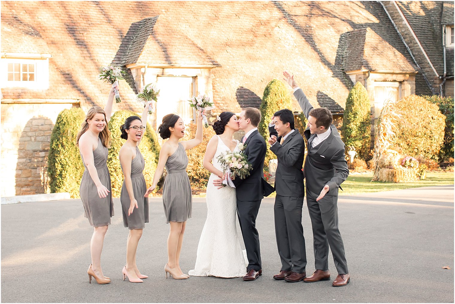 Bride and groom kissing and bridal party cheering