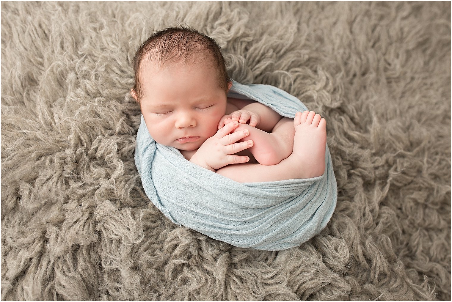 Newborn boy in light blue wrap