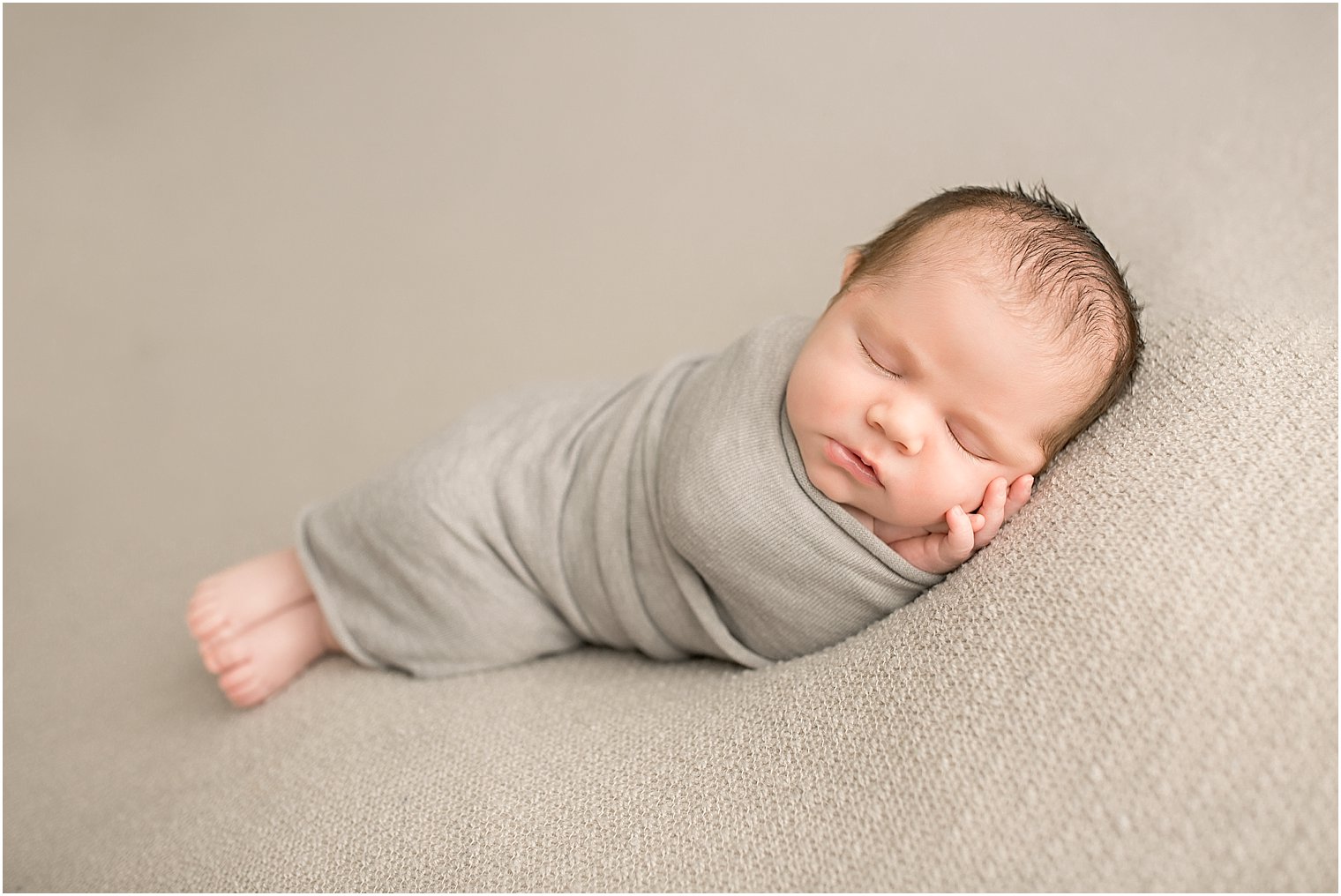 Newborn boy in gray wrap