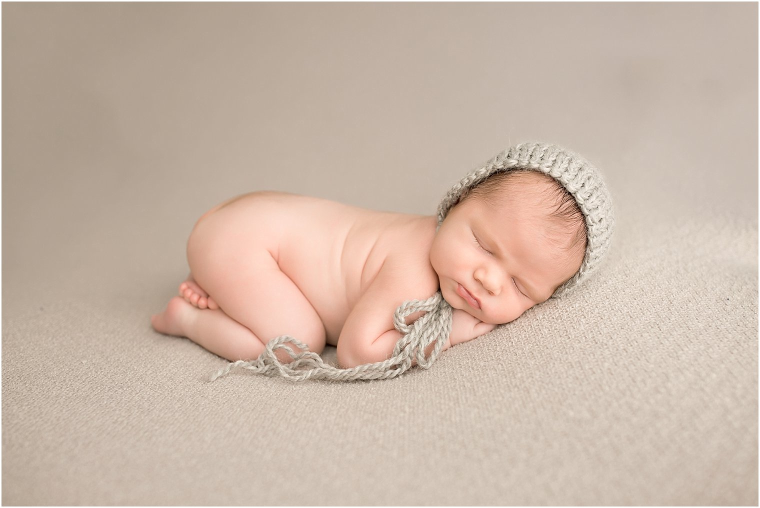Newborn boy sleeping on gray blanket