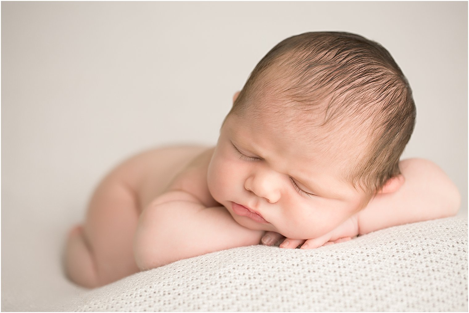 Newborn boy in chin on hands pose