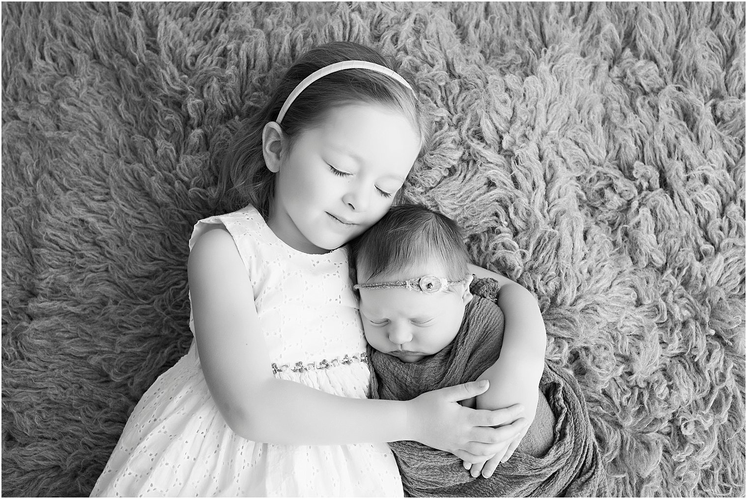 Black and white photo of big sister and newborn baby