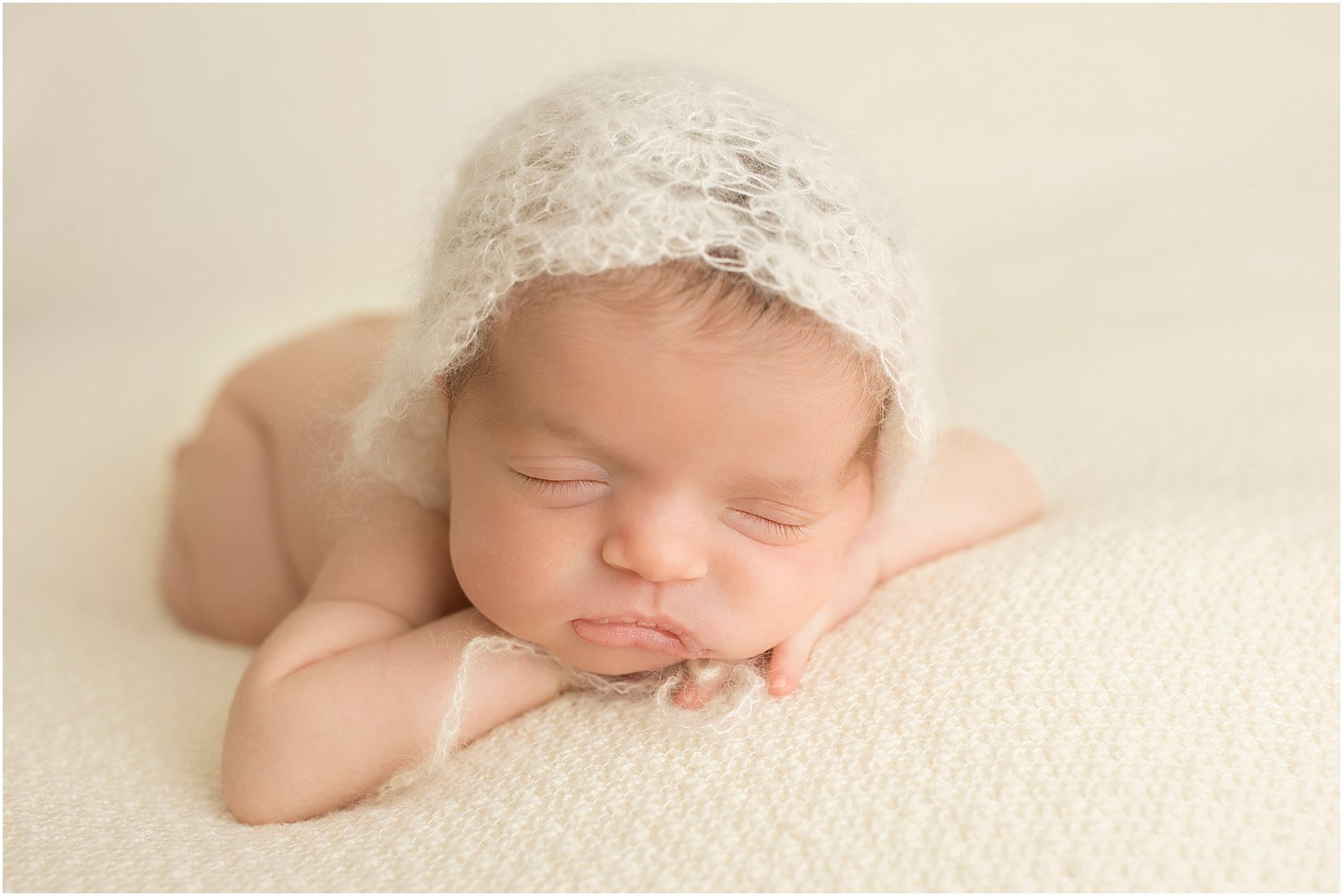 Sleeping newborn girl with cream knit bonnet
