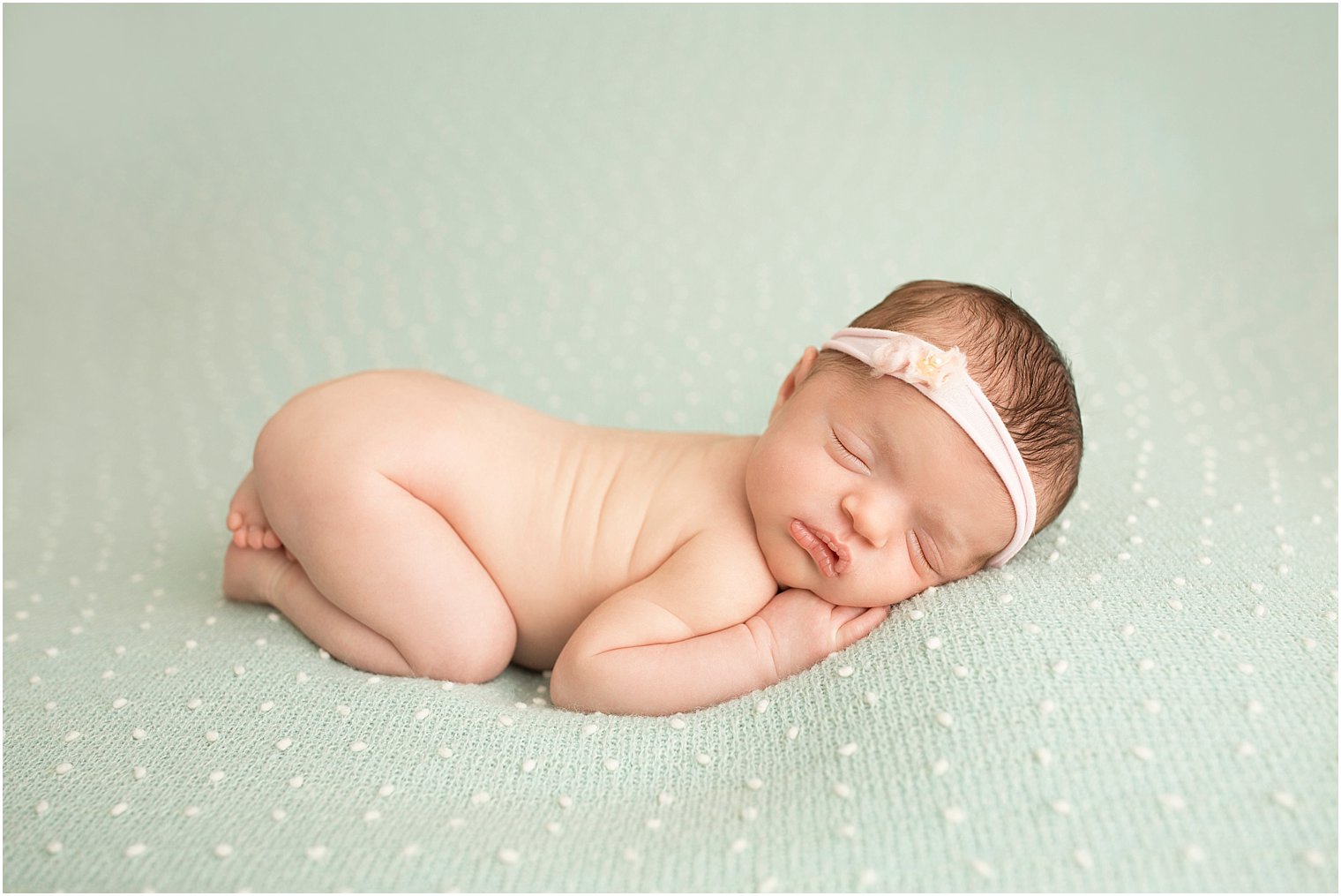 Newborn girl sleeping on green blanket during studio newborn session