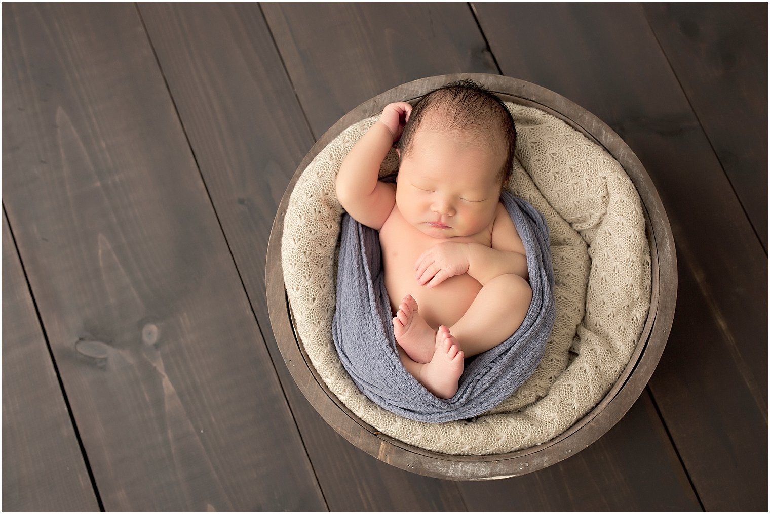 Photo of baby boy sleeping in a wooden basket