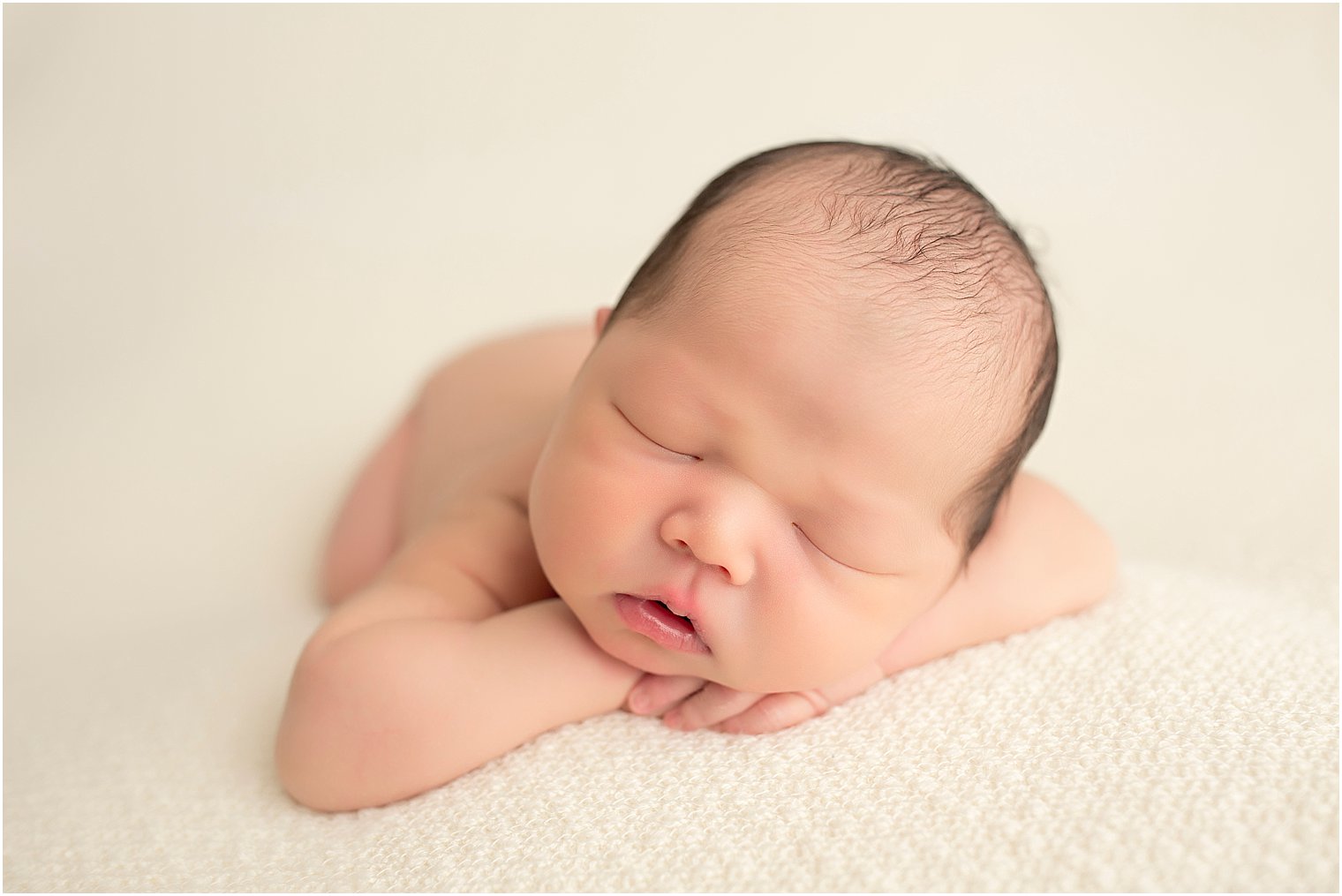 Newborn boy sleeping on cream blanket