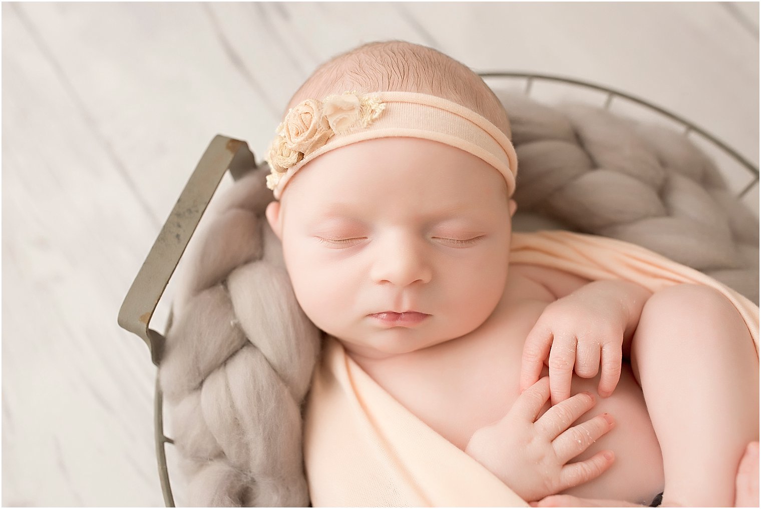Baby girl asleep in a wire basket during newborn session