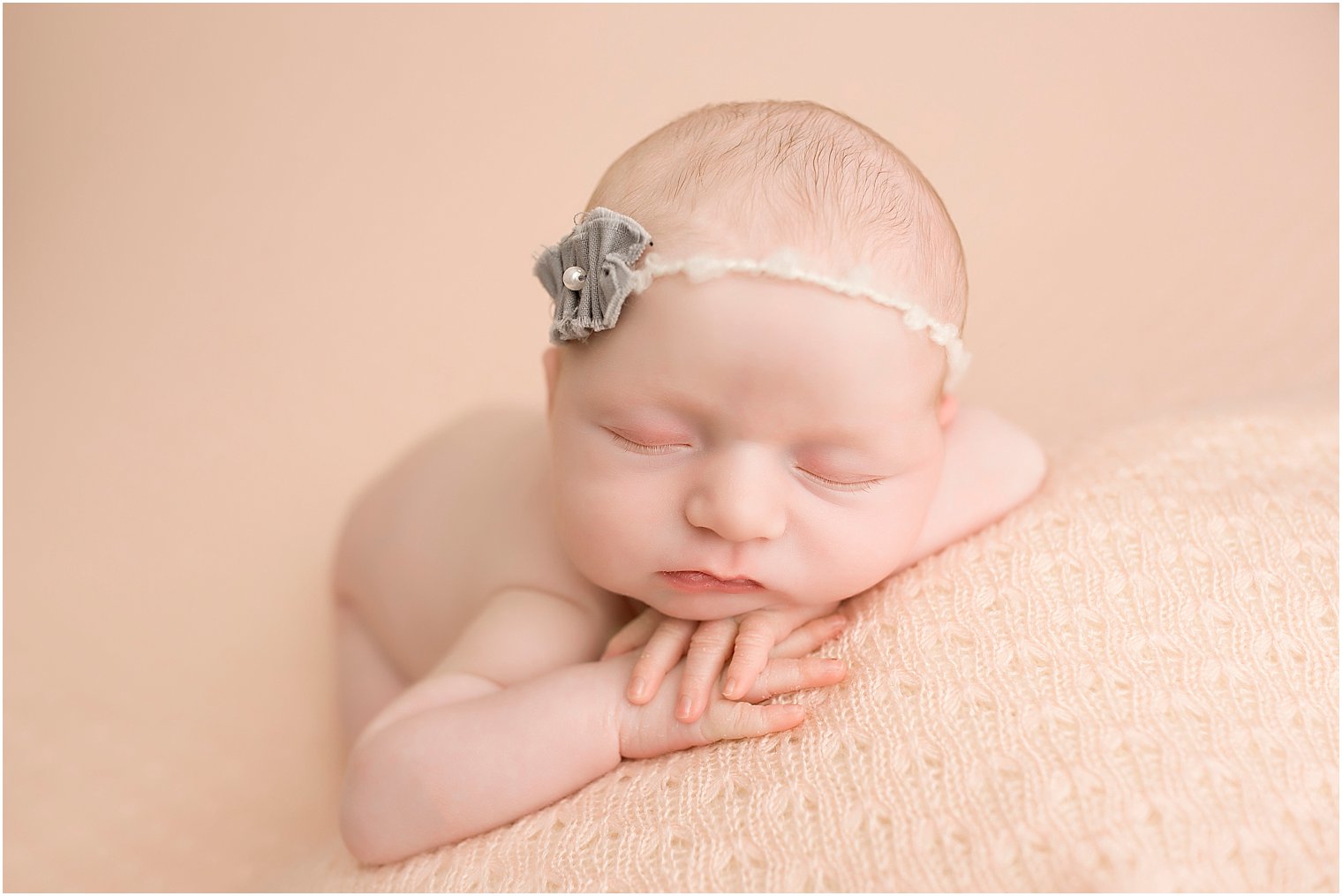 Newborn girl on pink blanket and wearing a gray headband