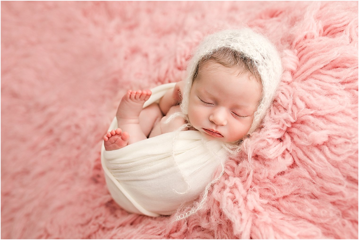 Newborn baby girl wearing a cream mohair bonnet