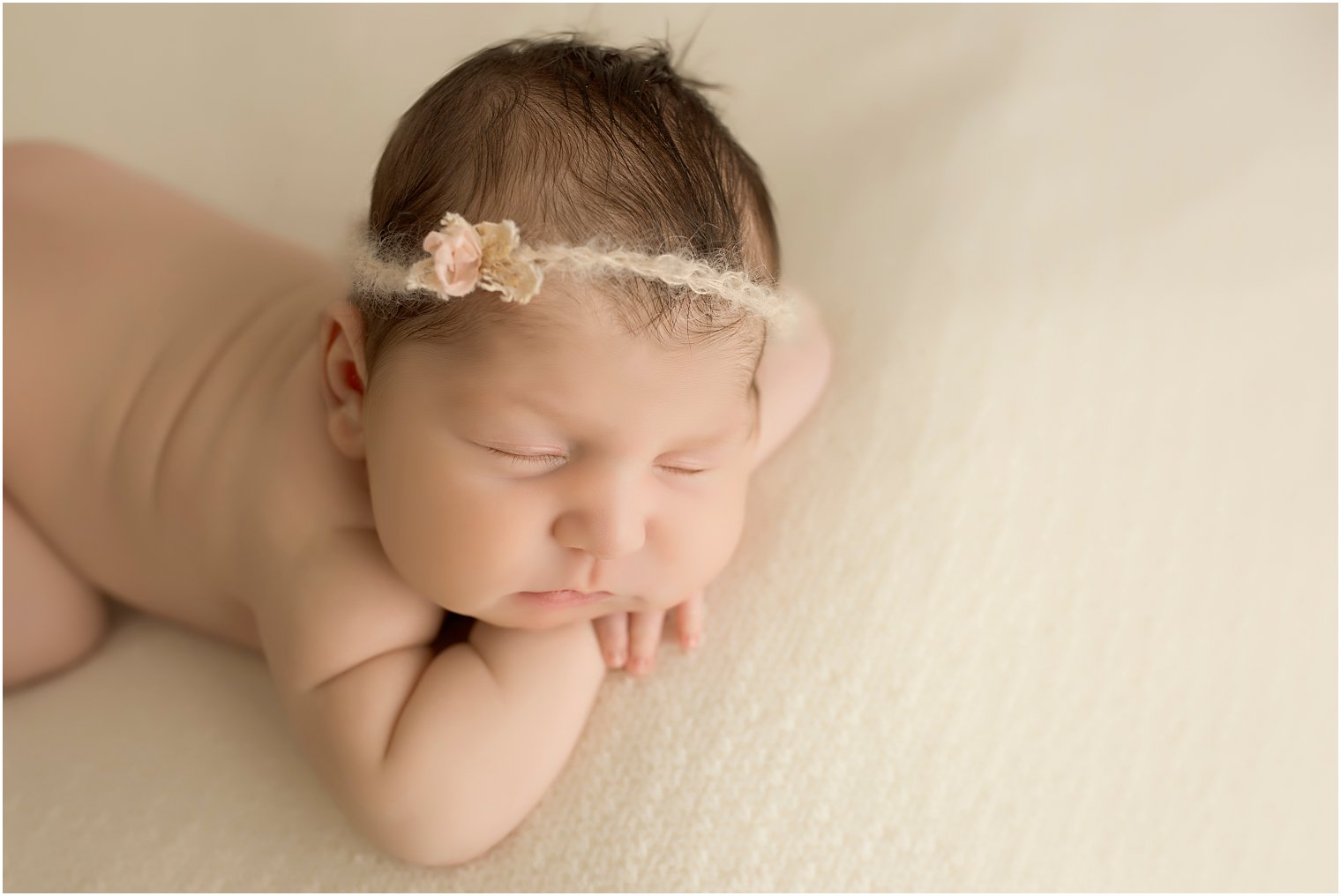 Newborn baby girl on cream blanket