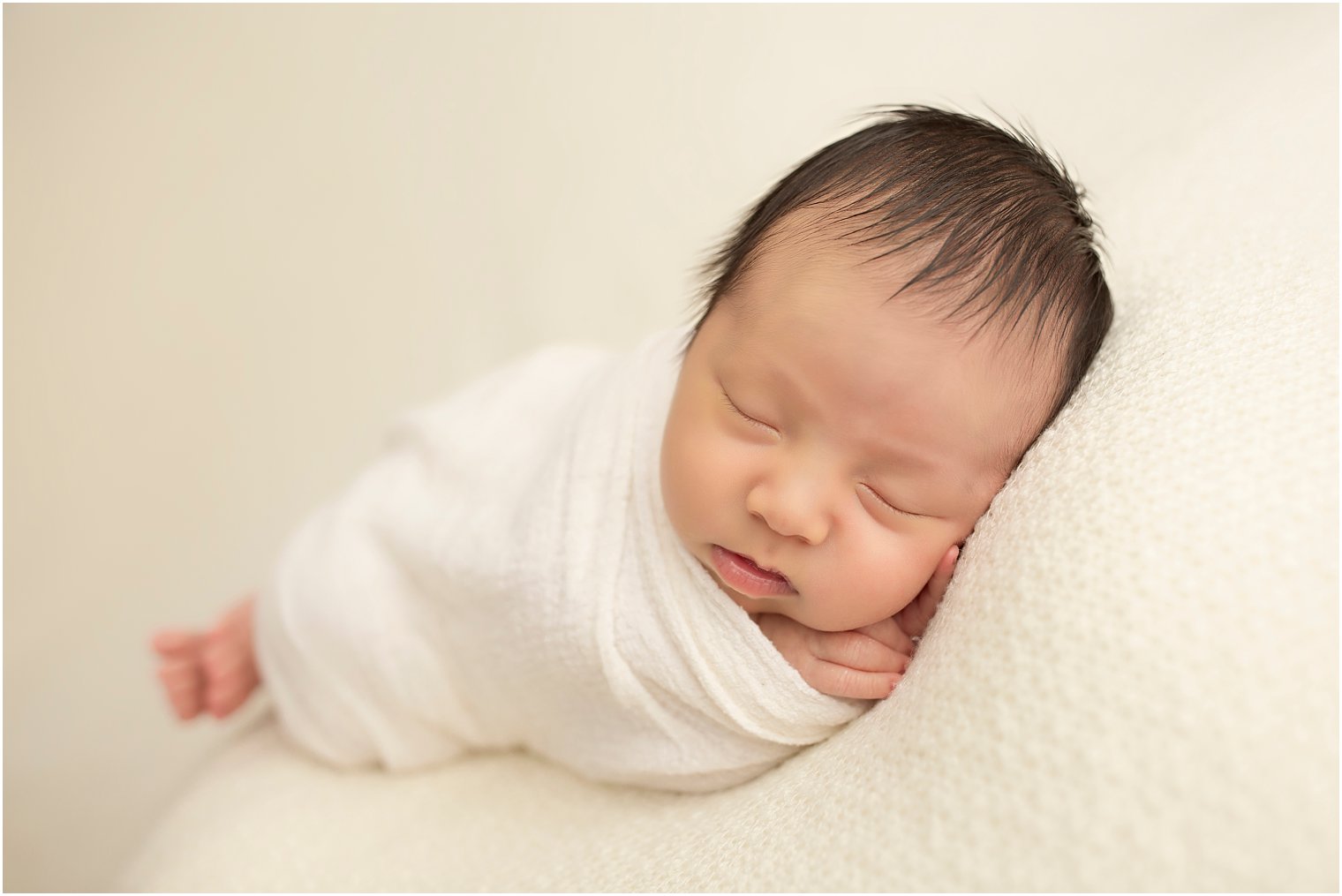 Newborn boy in cream blanket