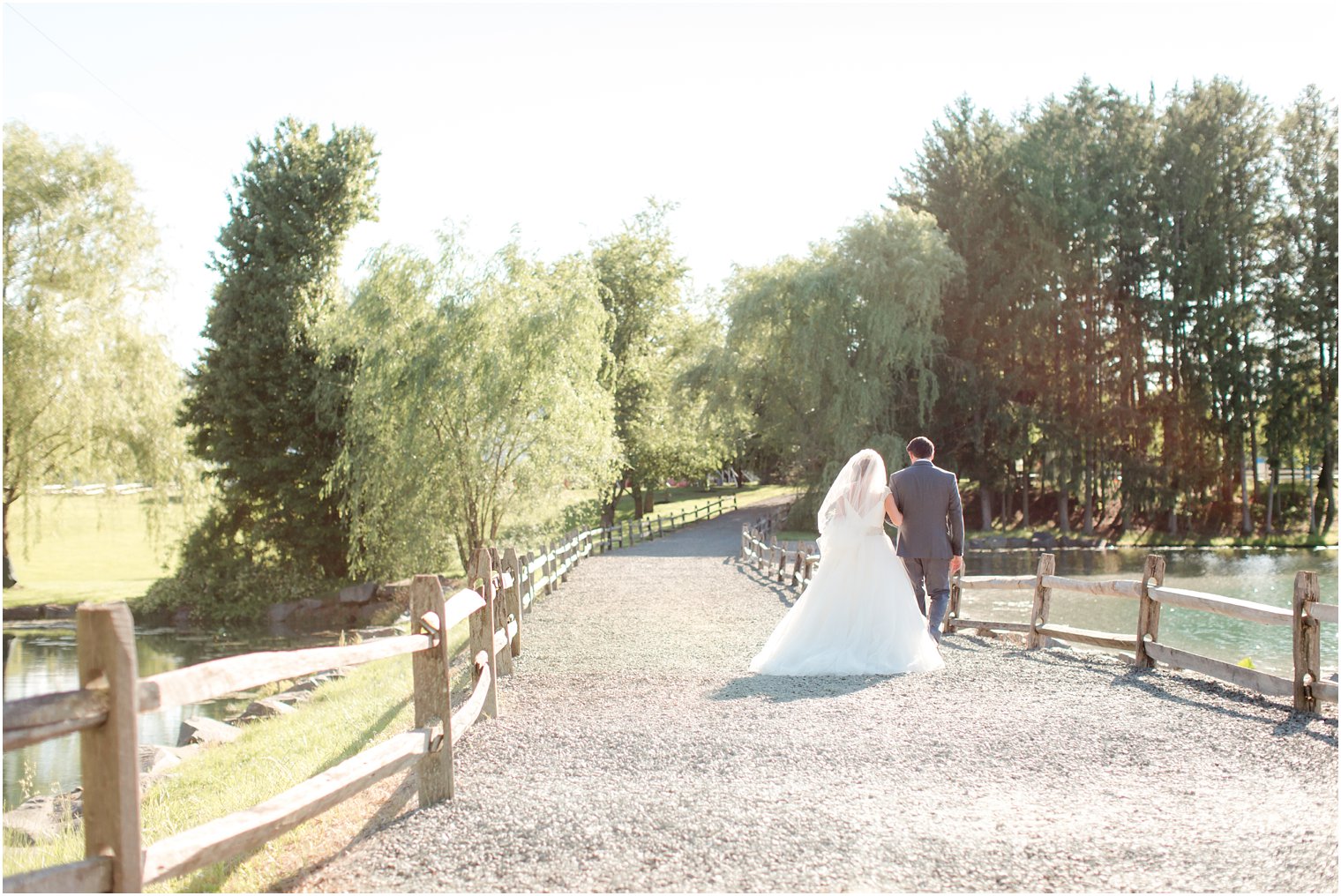 Bride and groom walking by willow trees at Windows on the Water at Frogbridge Wedding
