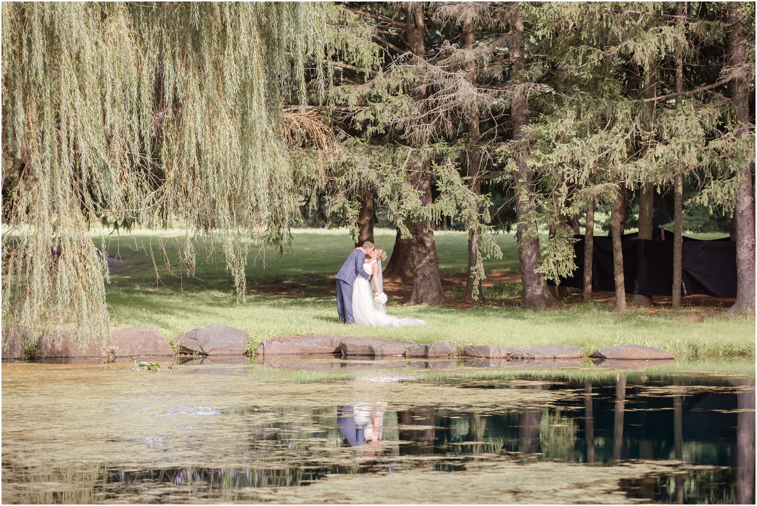 Romantic bride and groom photo by willow trees at Windows on the Water at Frogbridge Wedding