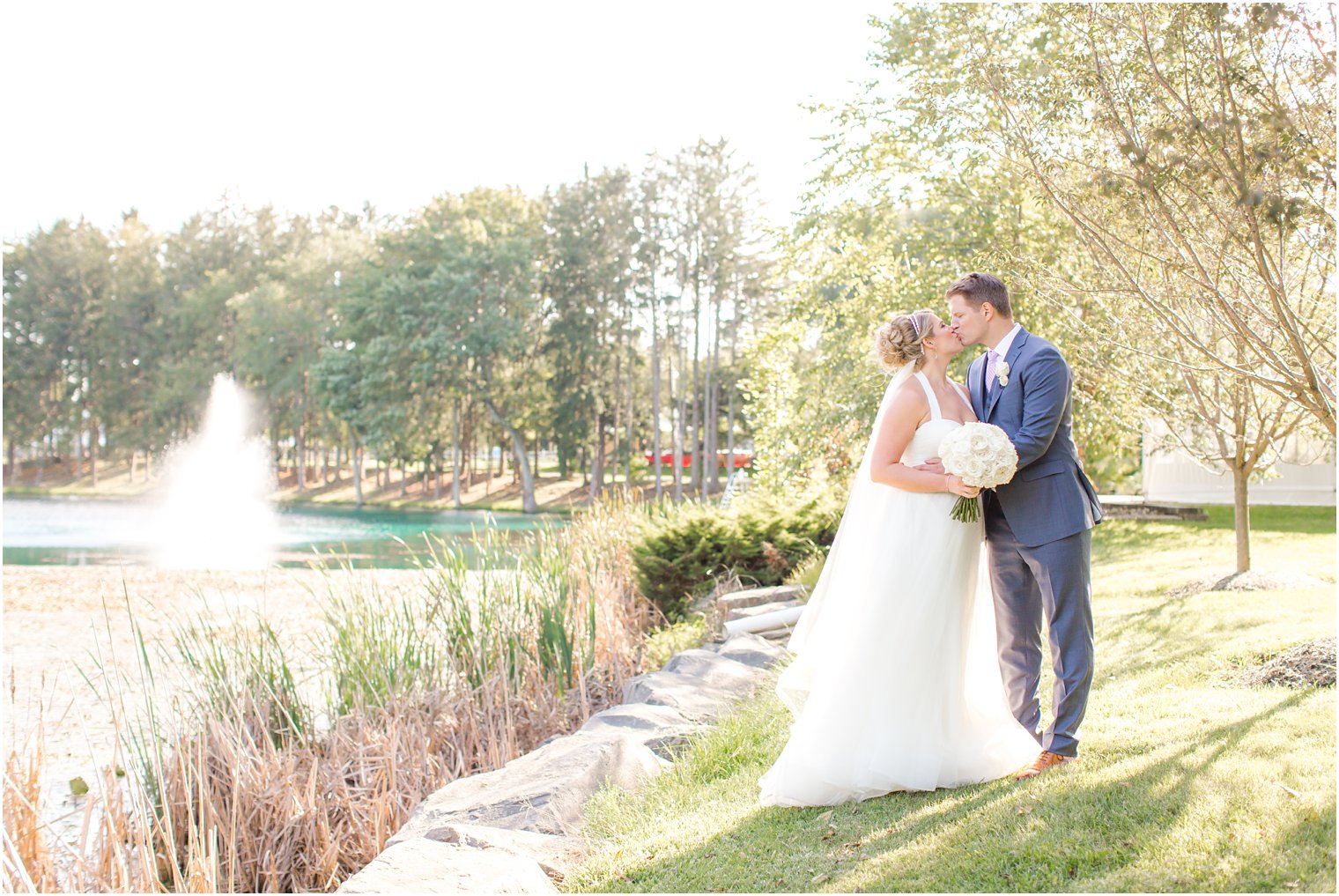 Romantic photo of bride and groom by pond 