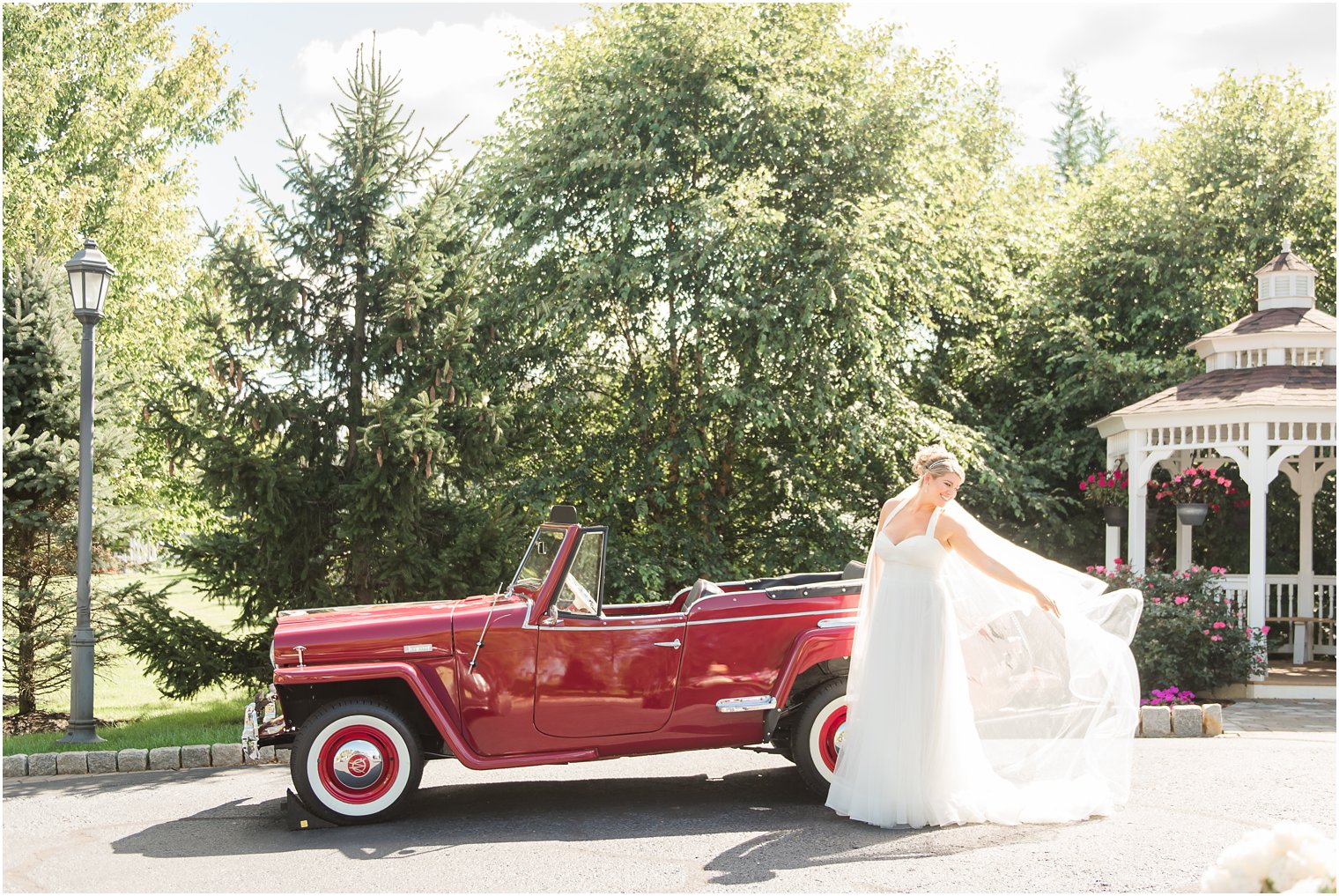Romantic bridal portrait with veil in front of red antique Jeepster