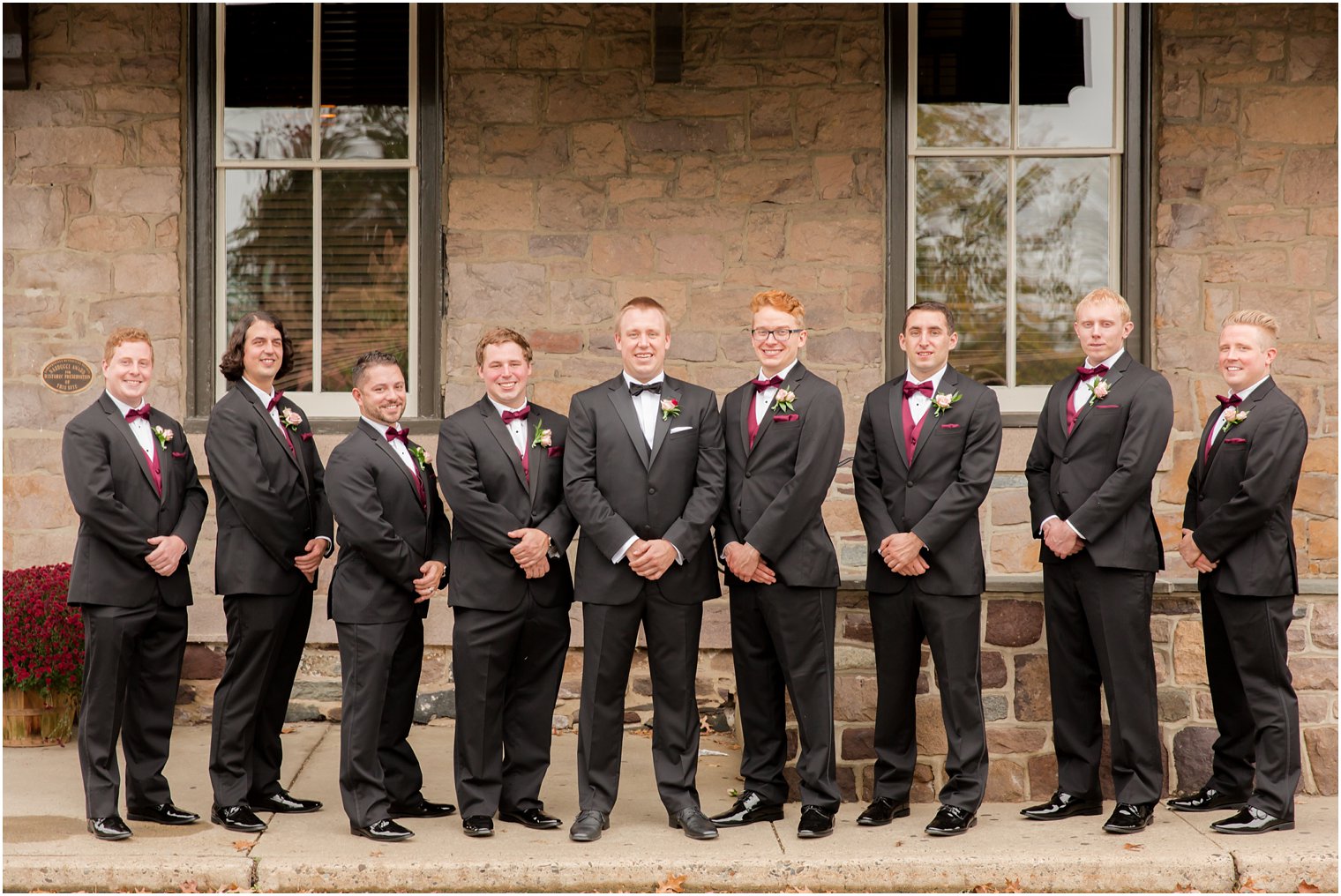 Groomsmen wearing black tuxedos and burgundy vest