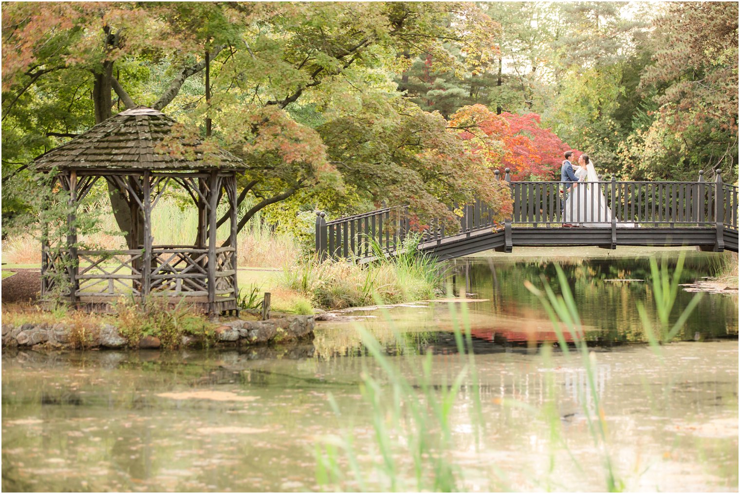 Fall wedding portrait with bridge and pond at Pleasantdale Chateau