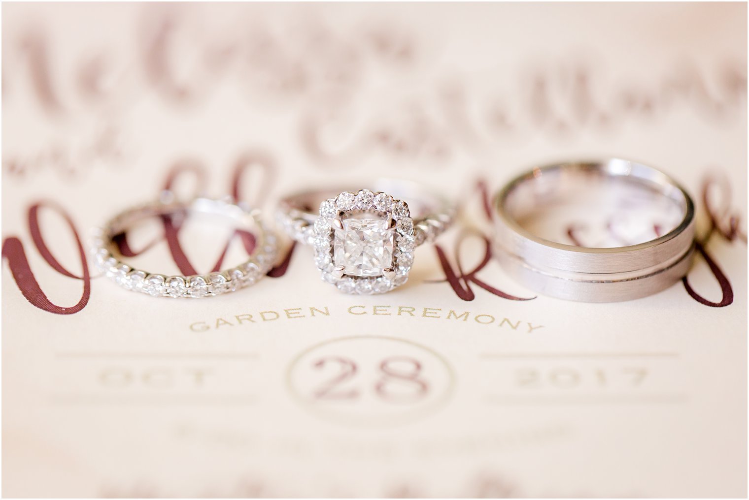 Wedding bands and engagement ring over invitation 