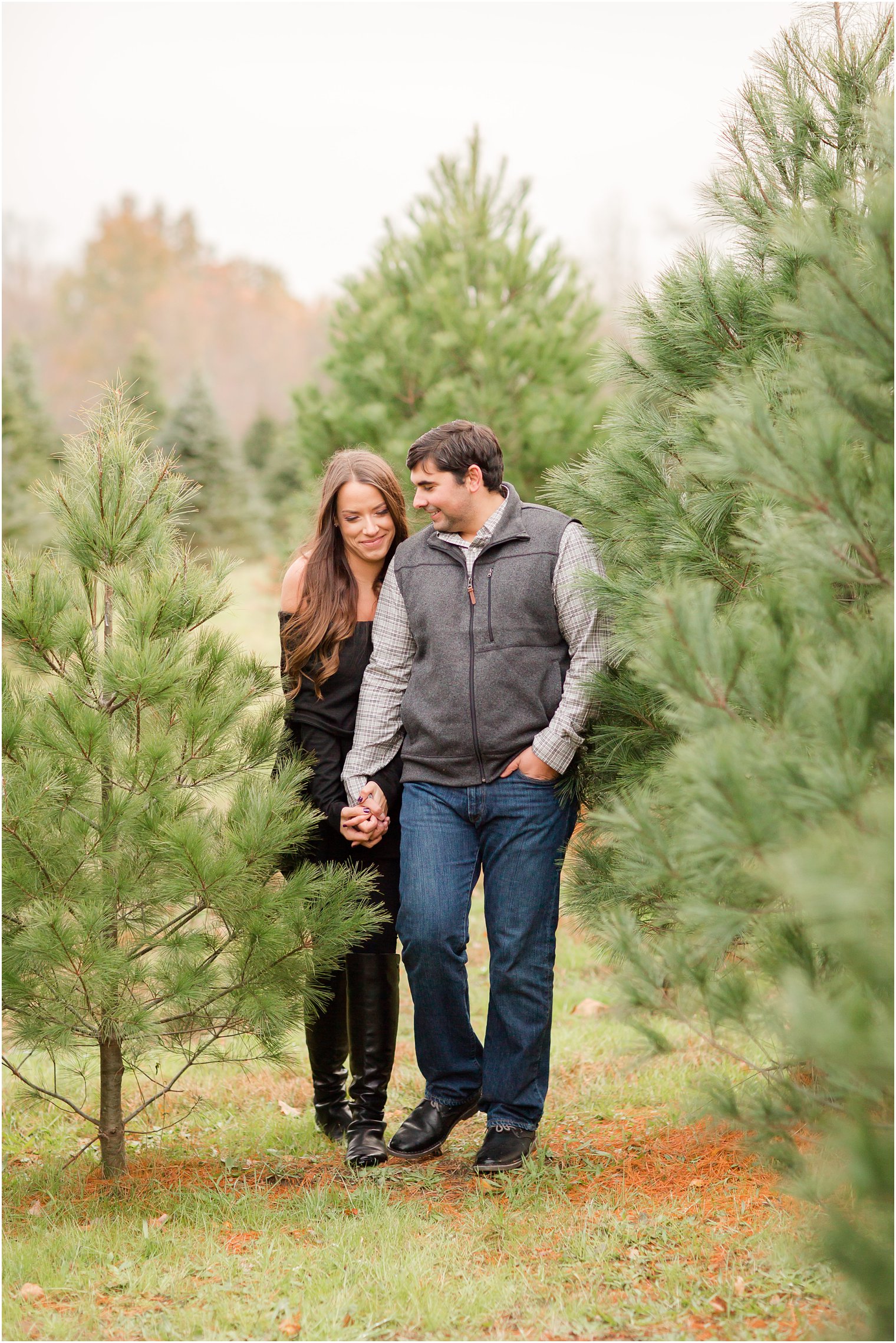 Engaged couple walking on a Christmas tree farm