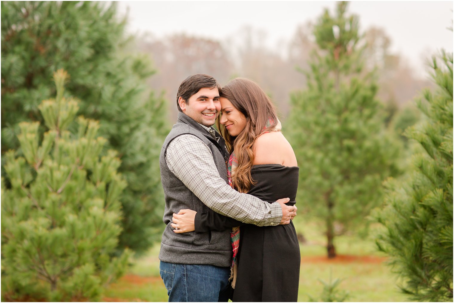 Couple hugging on a tree farm for Christmas