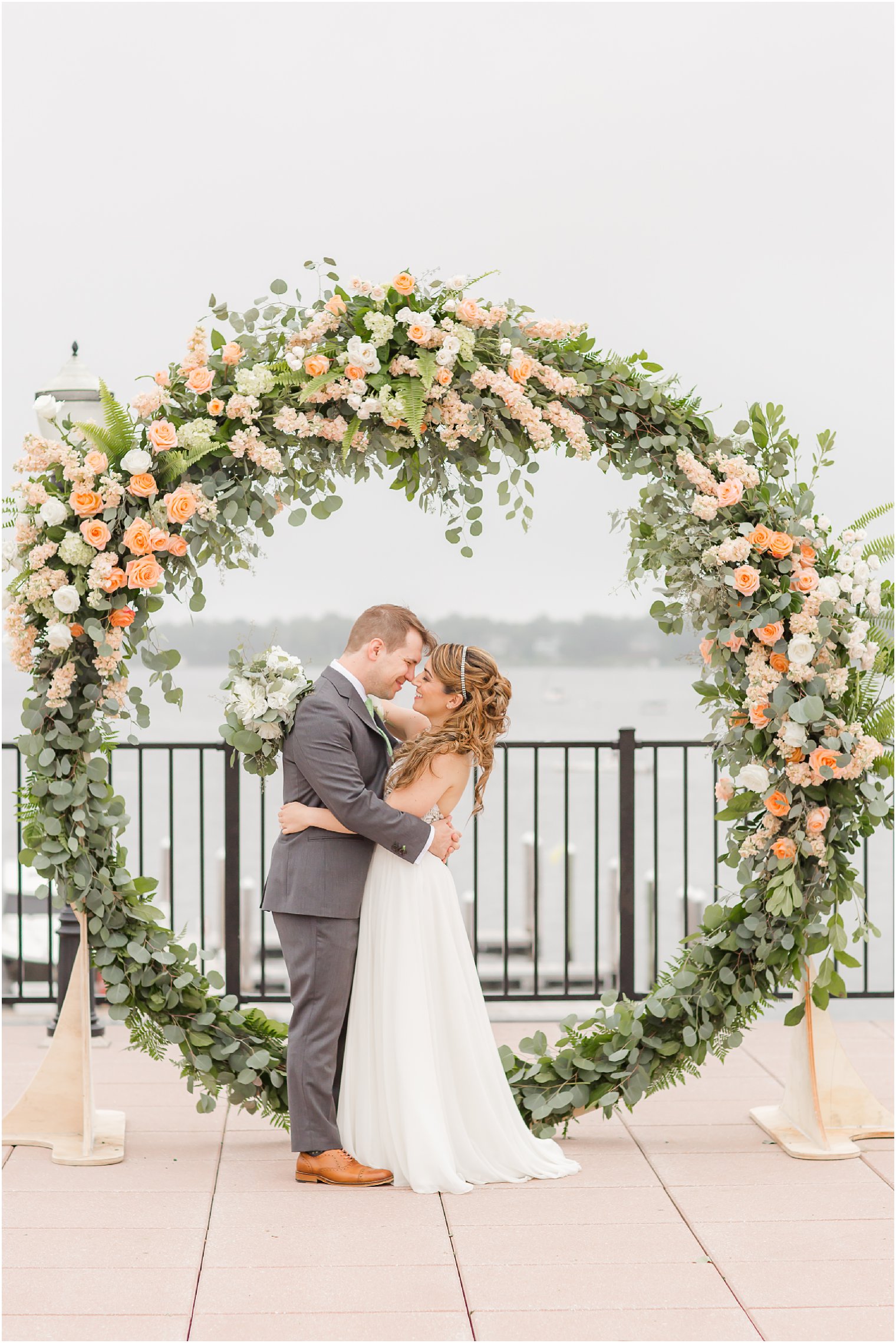 Bride and groom kissing by giant floral wreath by Craig Kiely and Darryn Murphy Designs