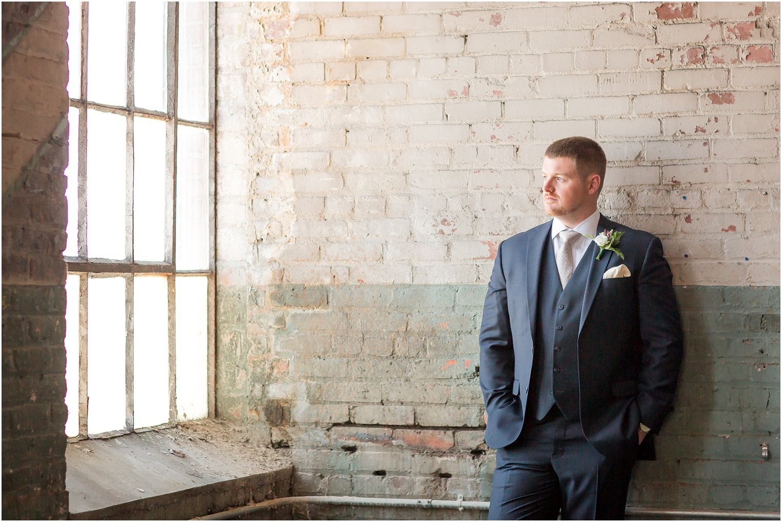 Groom posing with brick backdrop