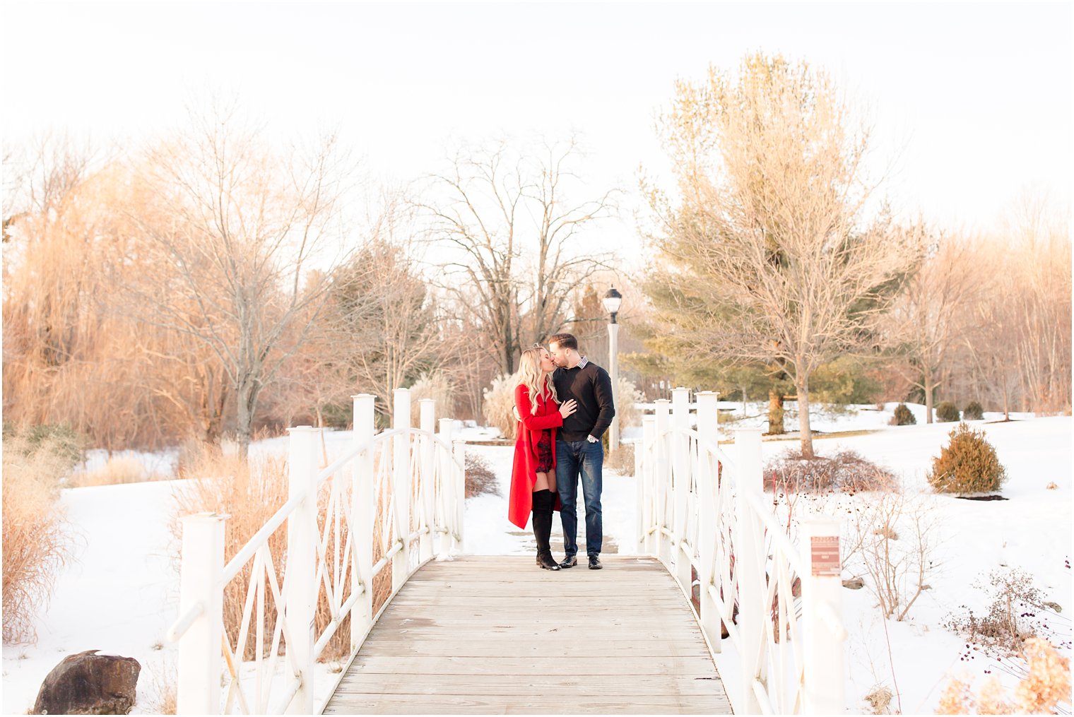 Couple walking and kissing on a snowy bridge