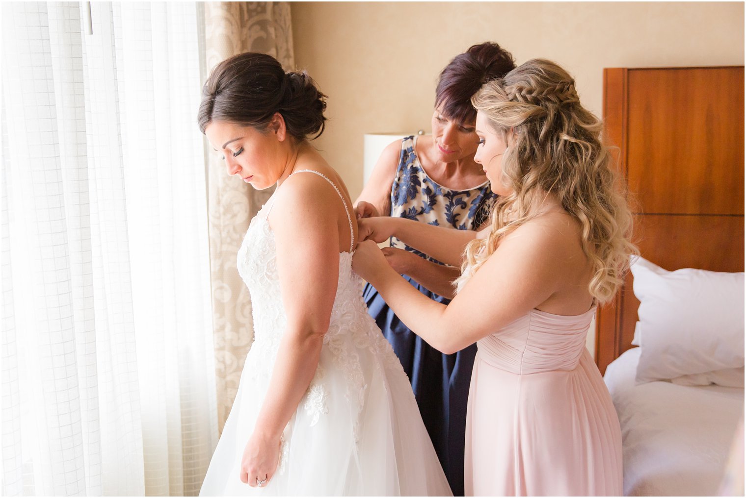 maid of honor and mother helping bride get dressed