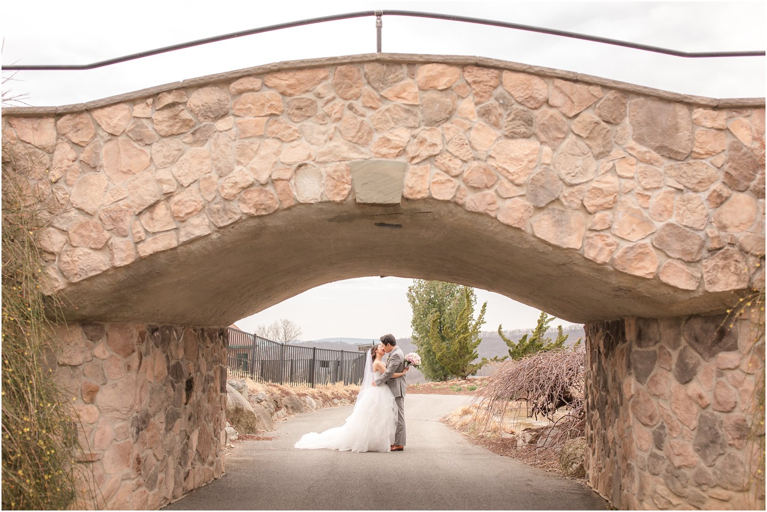 Bride and groom under stone bridge at Grand Cascades Lodge