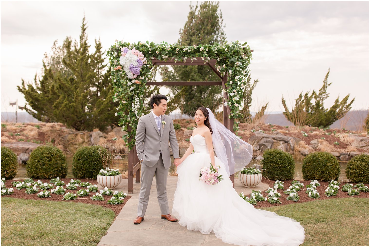 Bride and groom posing for photos under ceremony arbor