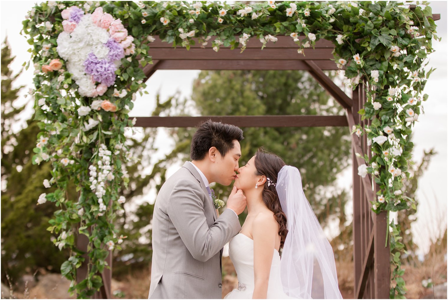 Bride and groom kissing under wedding arbor