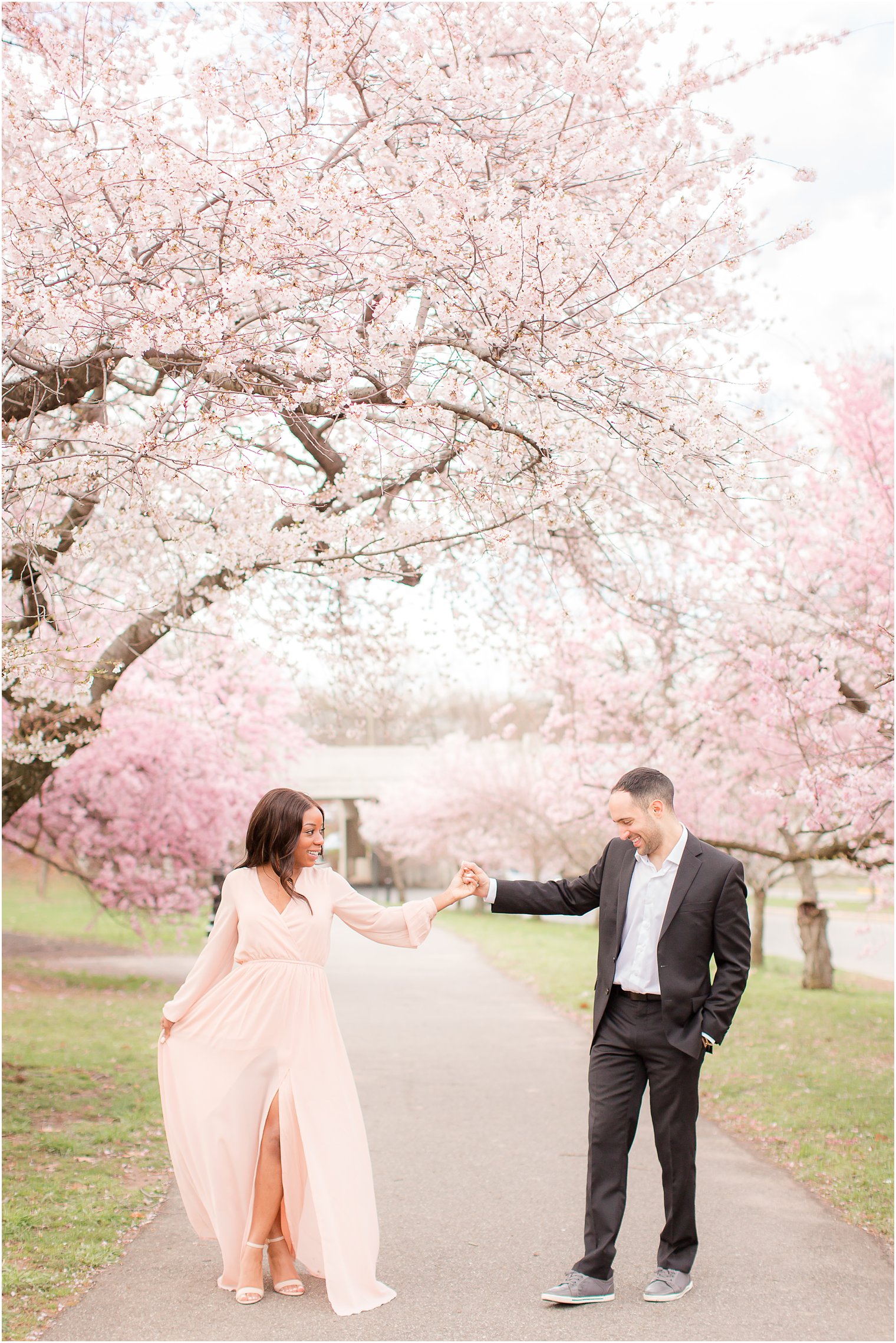 couple dancing during epic engagement session with cherry blossoms