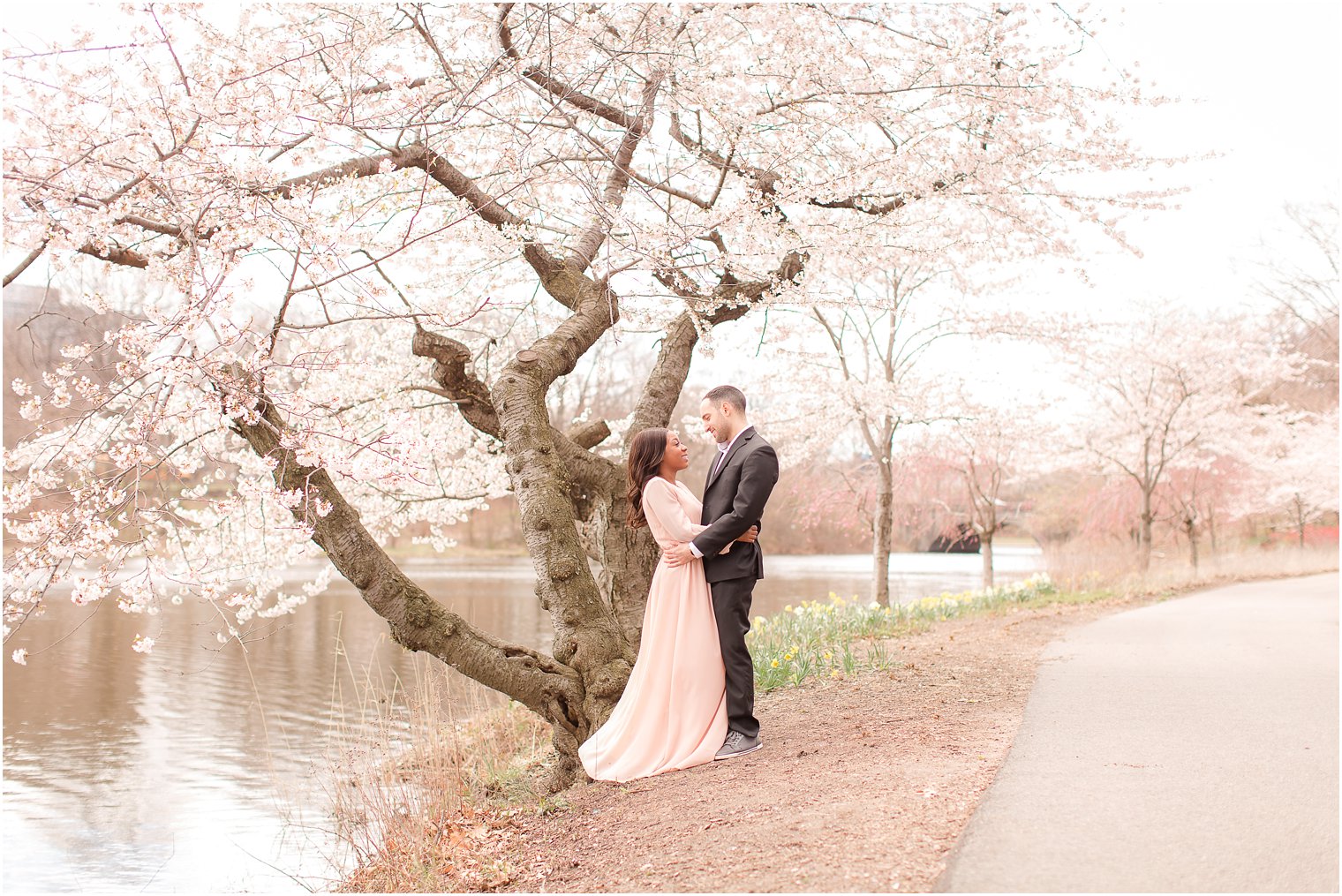 bride and groom standing near cherry blossom tree