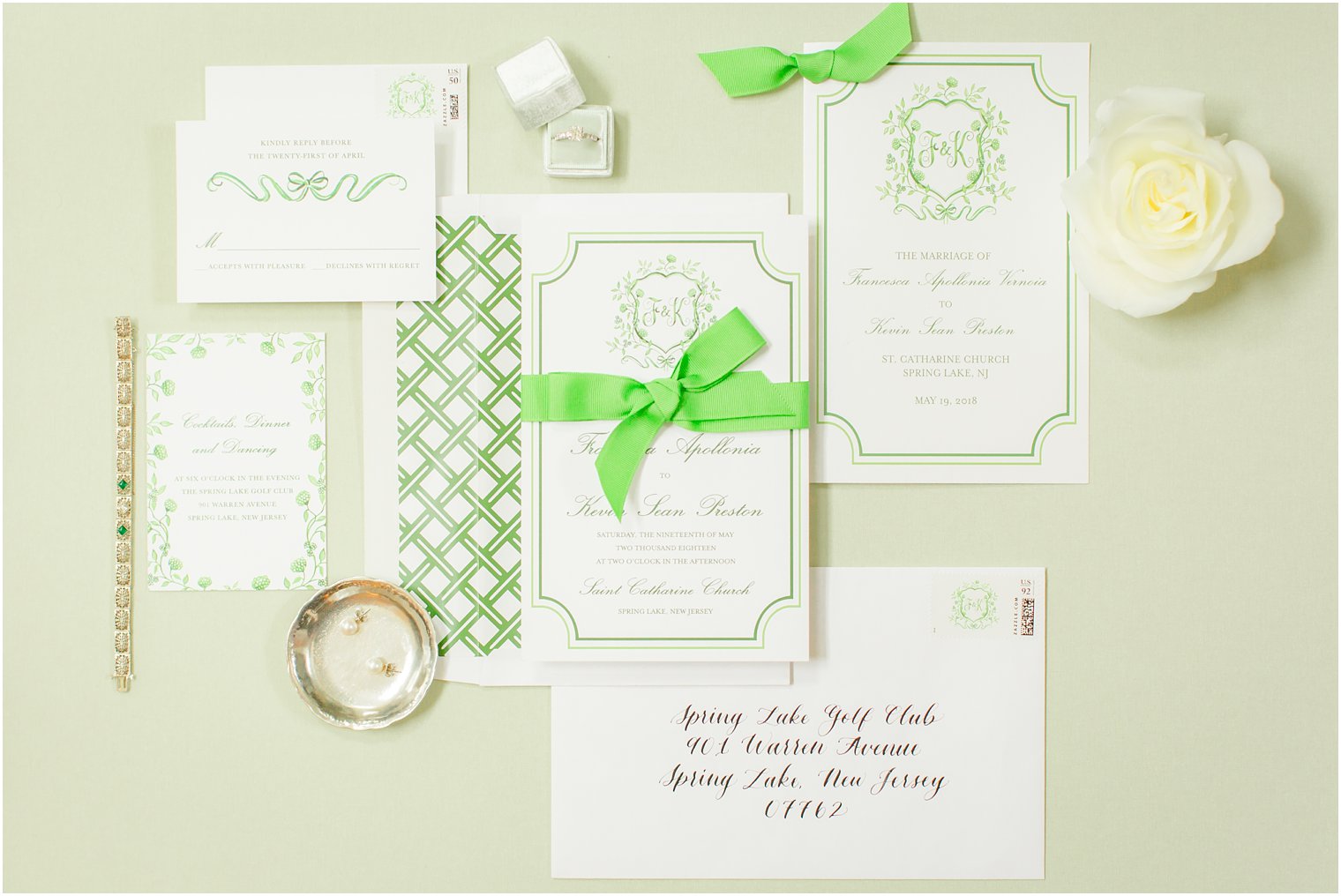 invitation suite on green styling board and invitation with custom wedding crest