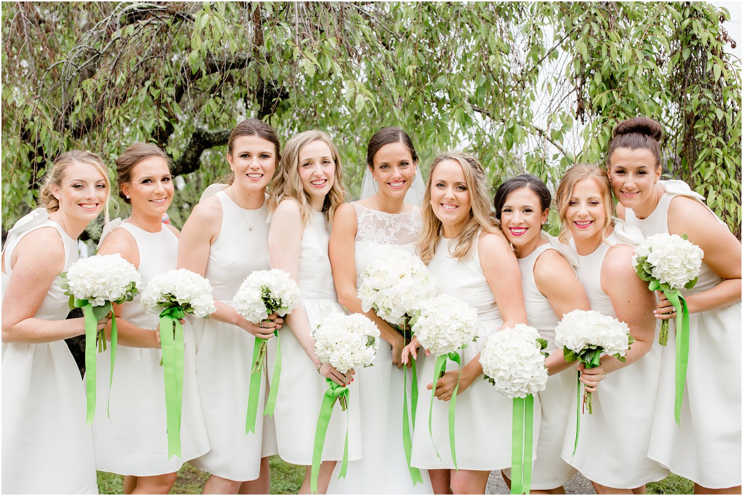 bridesmaids in short white dresses and green ribbons