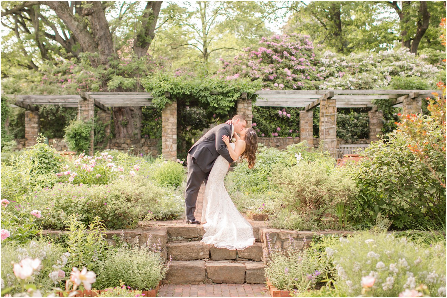 groom dipping bride in the middle of a lush garden