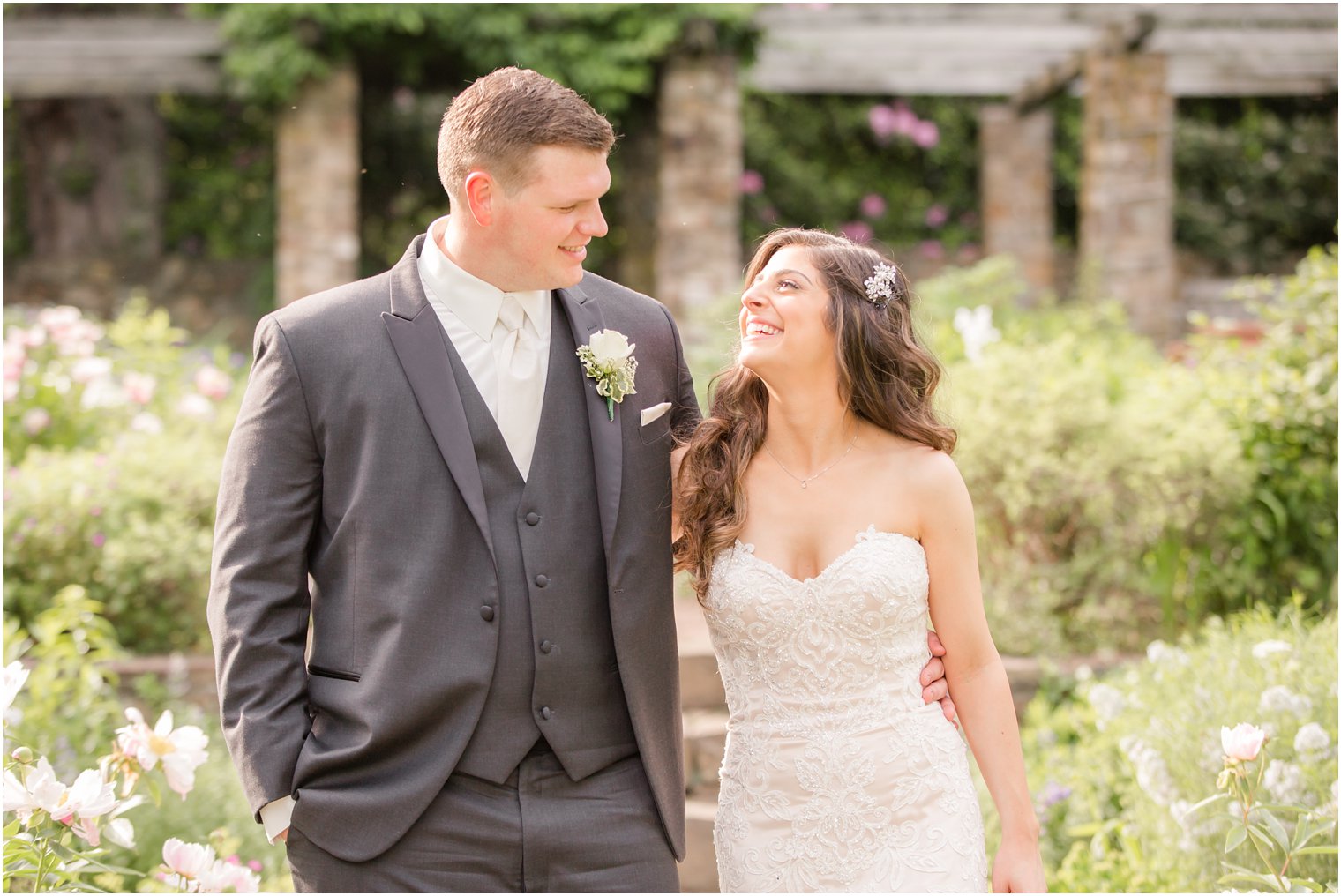 happy bride and groom walking through a garden