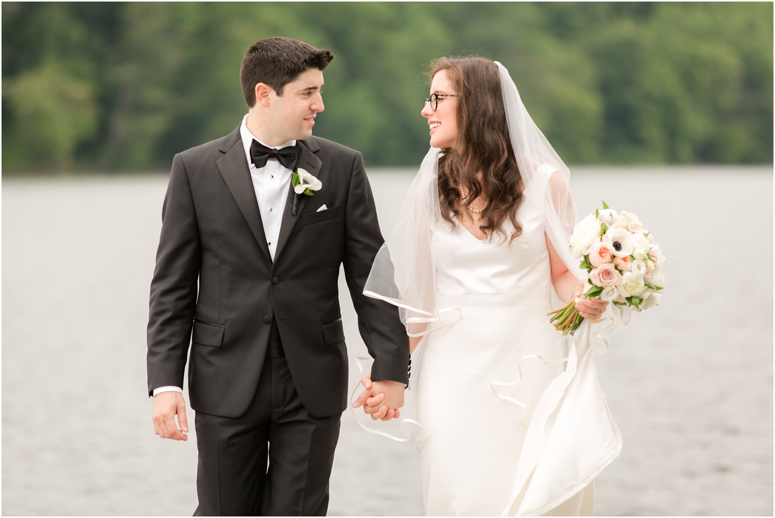 bride and groom walking away from a lake