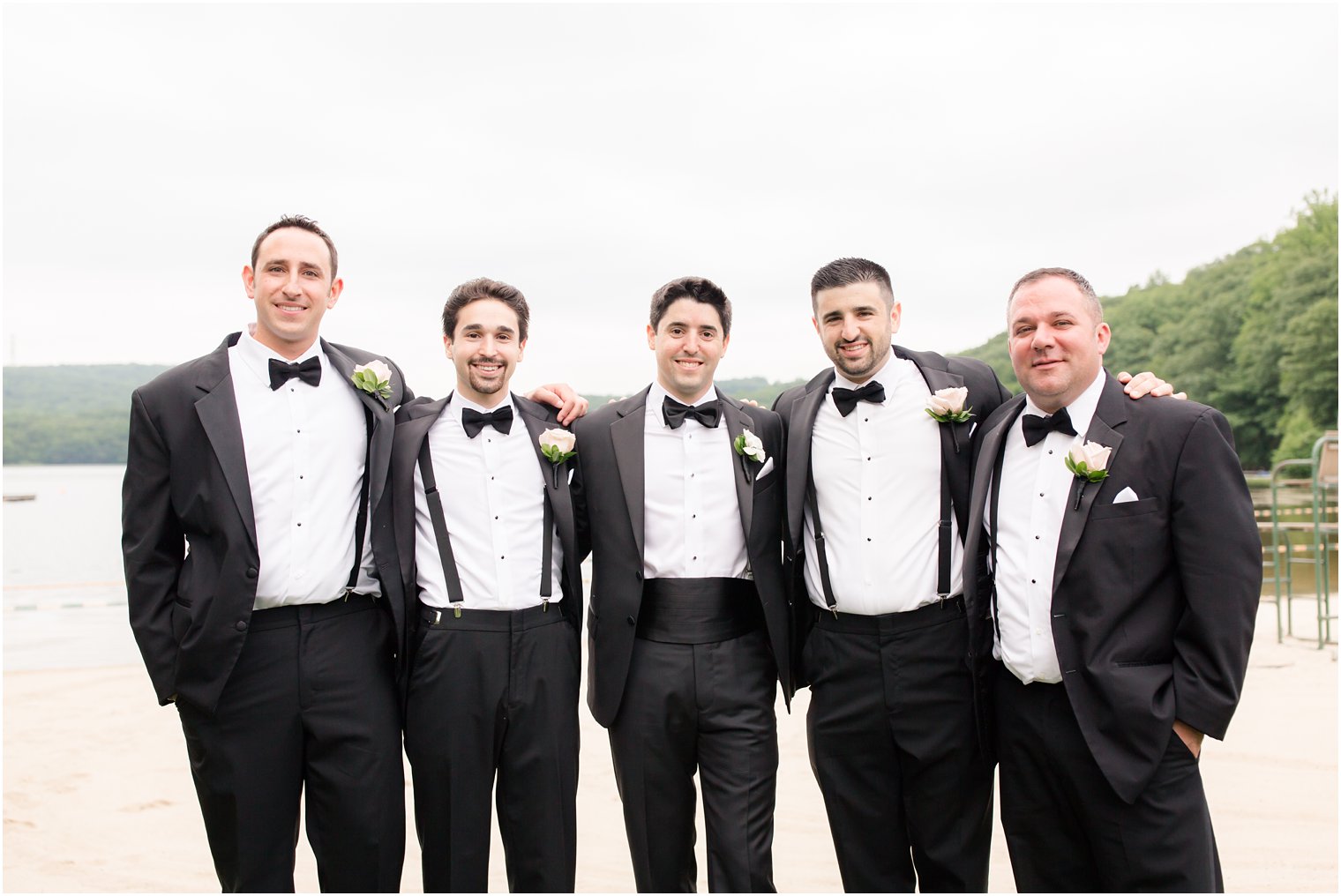 groomsmen wearing black tuxedos and suspenders